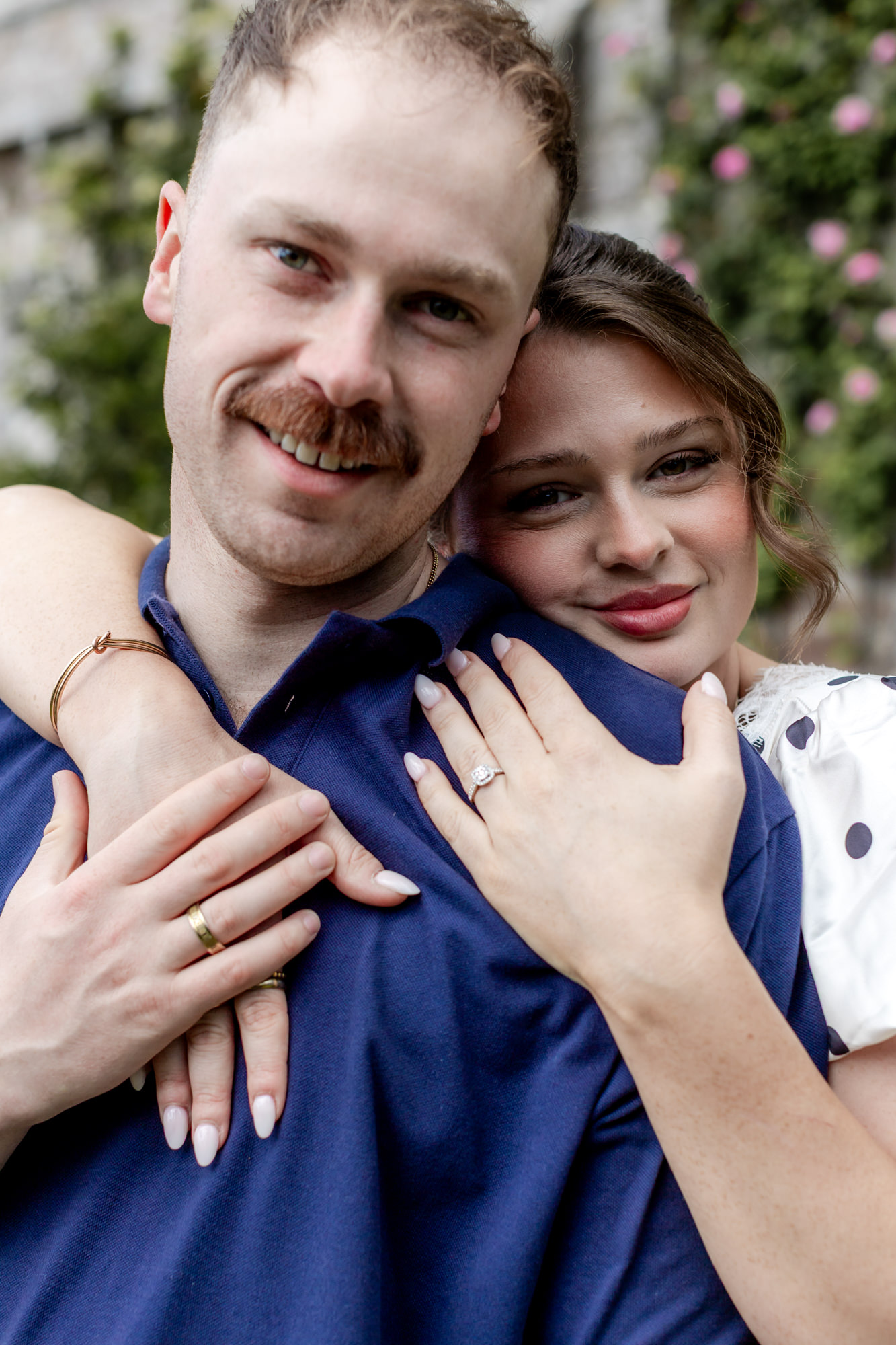 woman embracing her fiance from behind, showing her engagement ring on her finger
