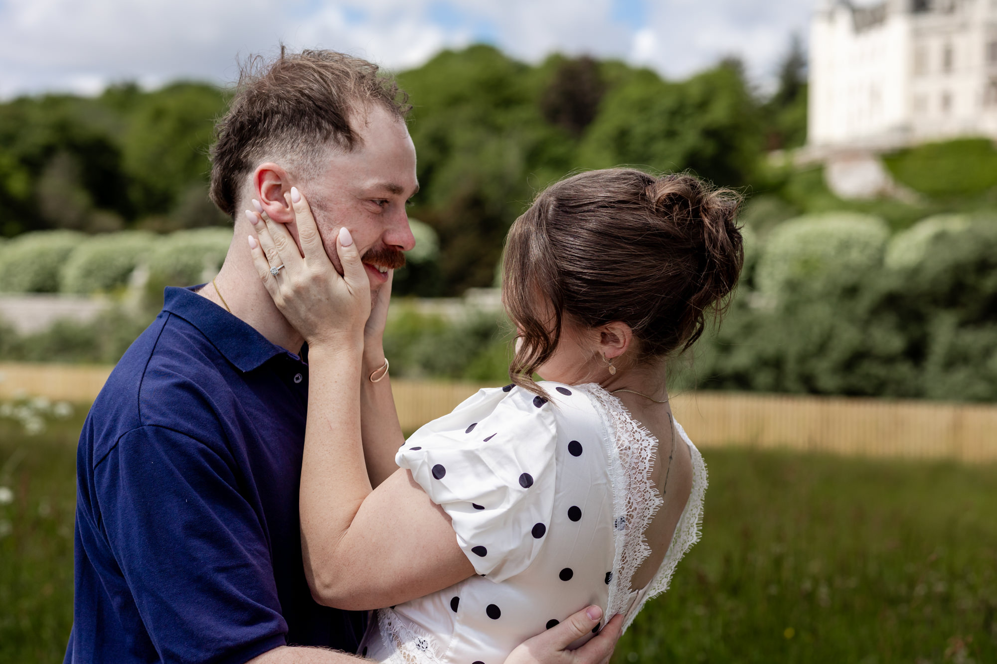 woman embracing her fiance's face in front of Dunrobin castle