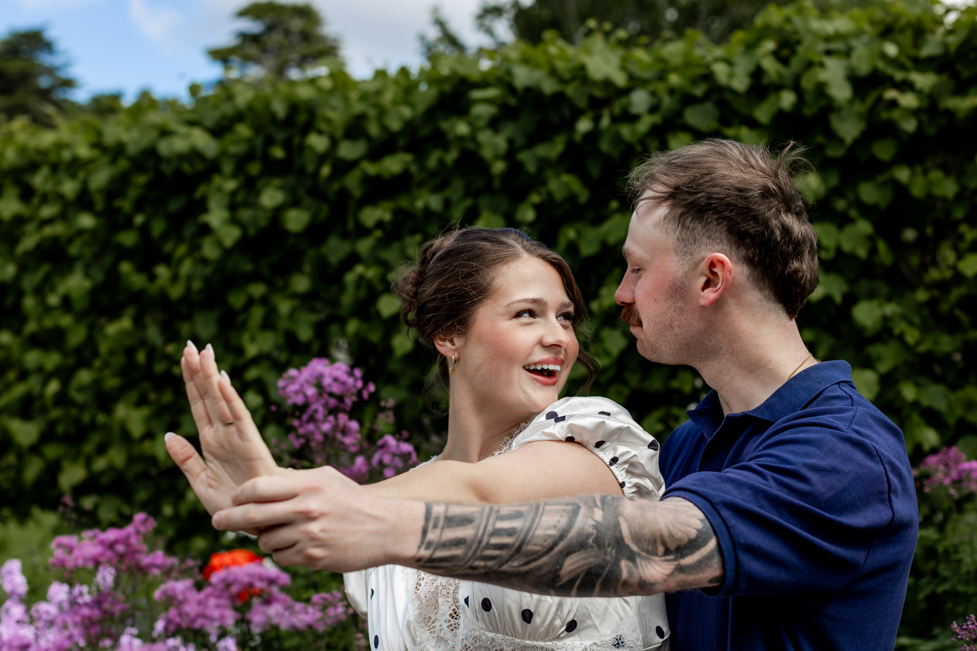 couple smiling at each other, admiring the engagement ring on the woman's finger
