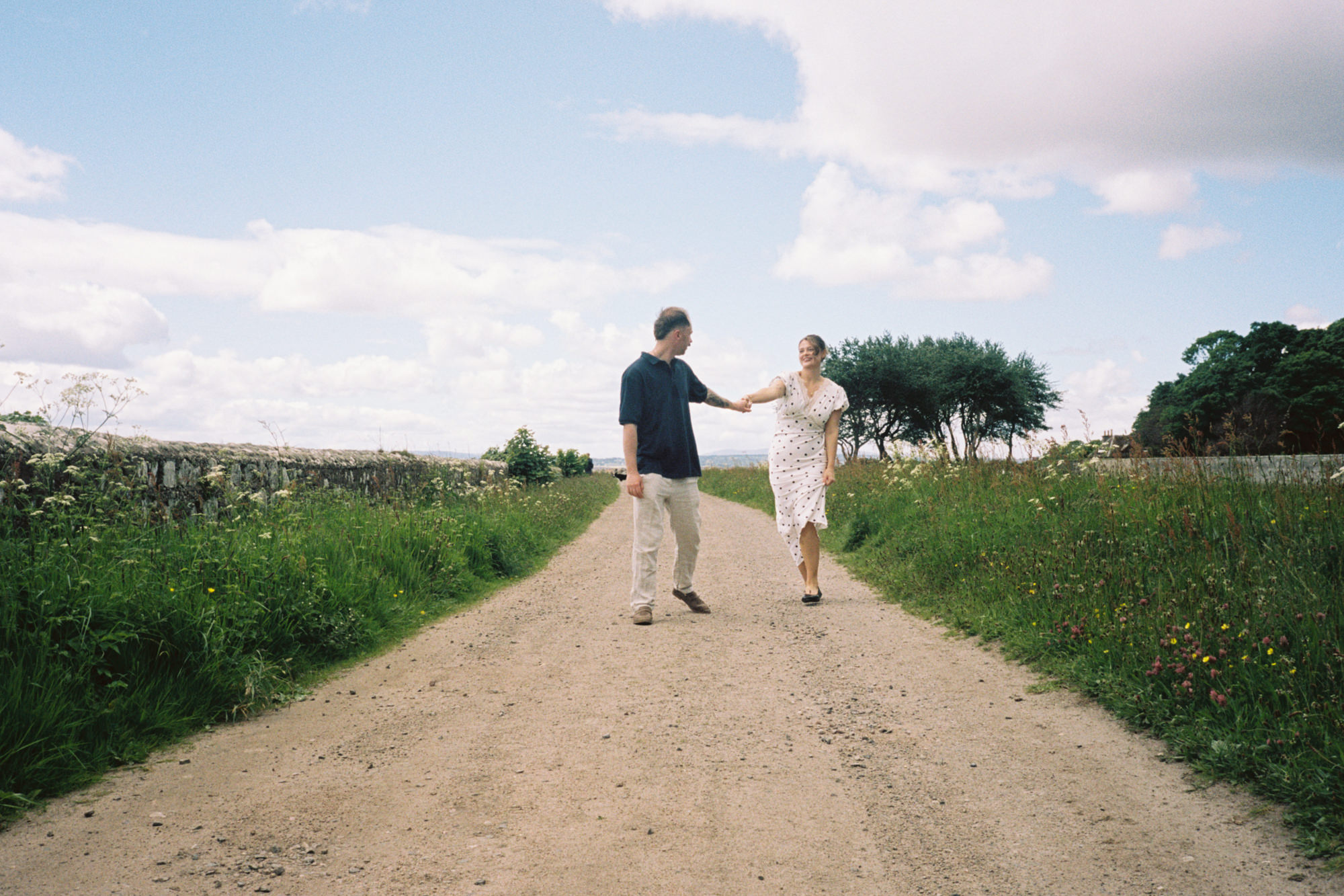 man and woman playfully walking along a track on a sunny summer day in the Scottish Highlands