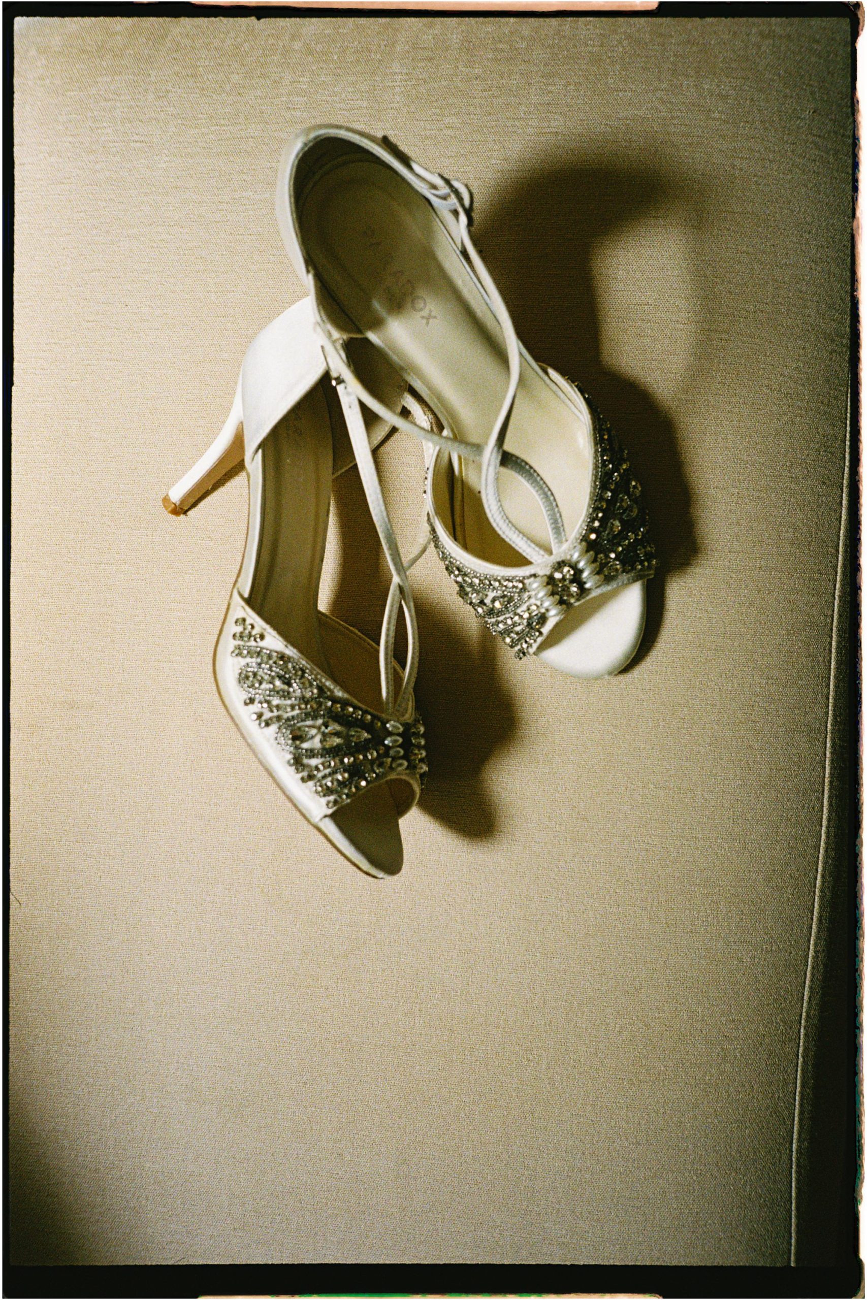analogue photo of bridal wedding shoes on a sofa